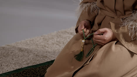 Close-Up-Of-Muslim-Woman-With-Prayer-Beads-At-Home-Praying-Kneeling-On-Prayer-Mat-1